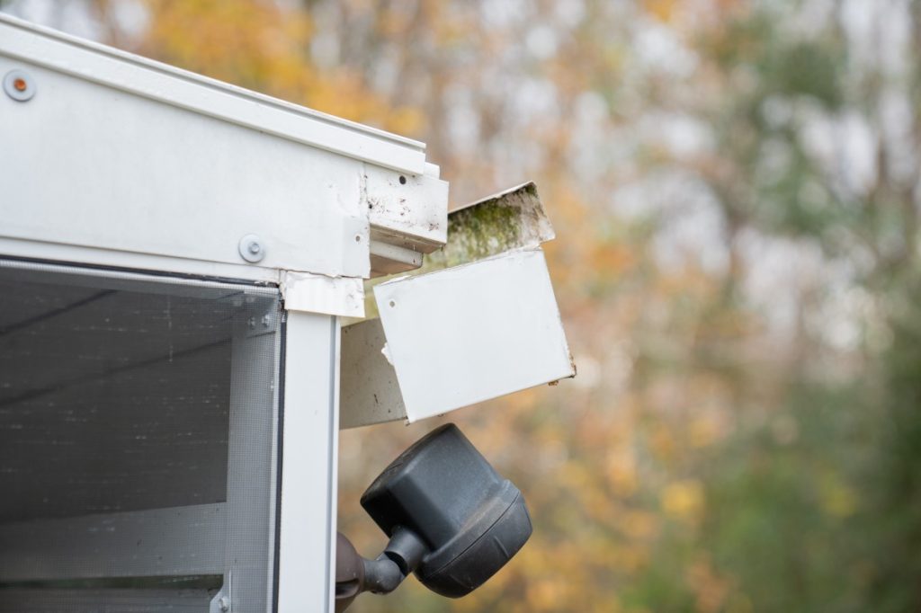 A white gutter end cap and downspout at a roof corner