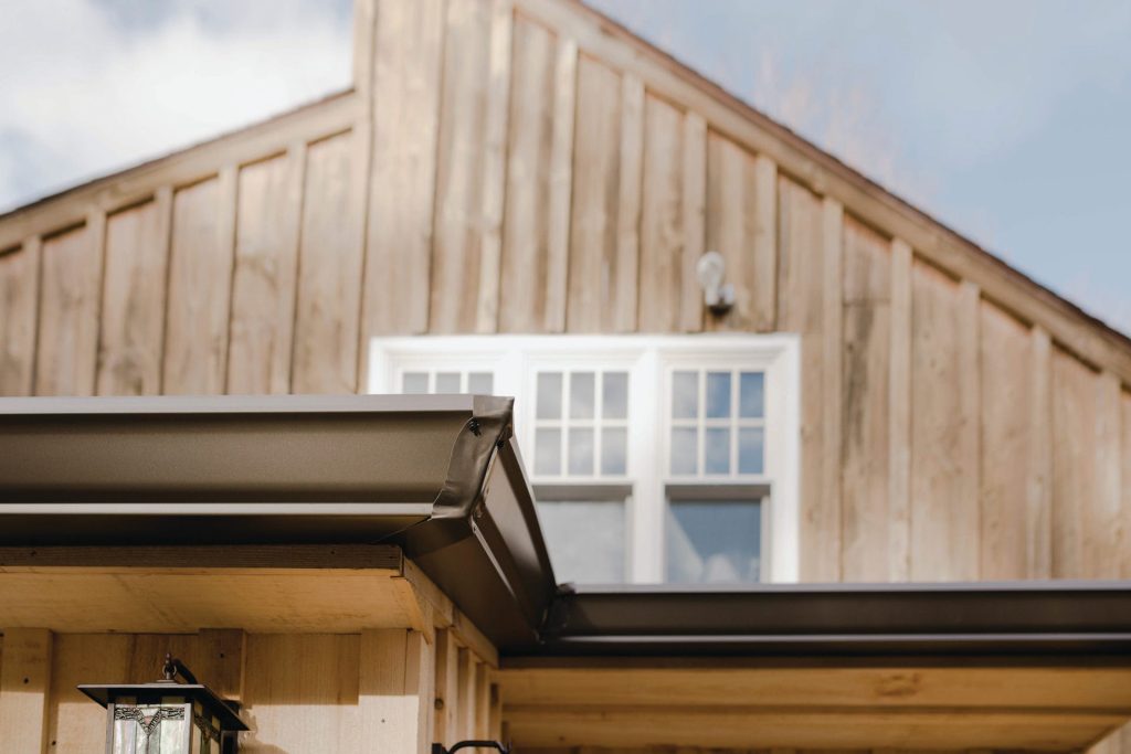 Bronze gutters on a board and batten facade