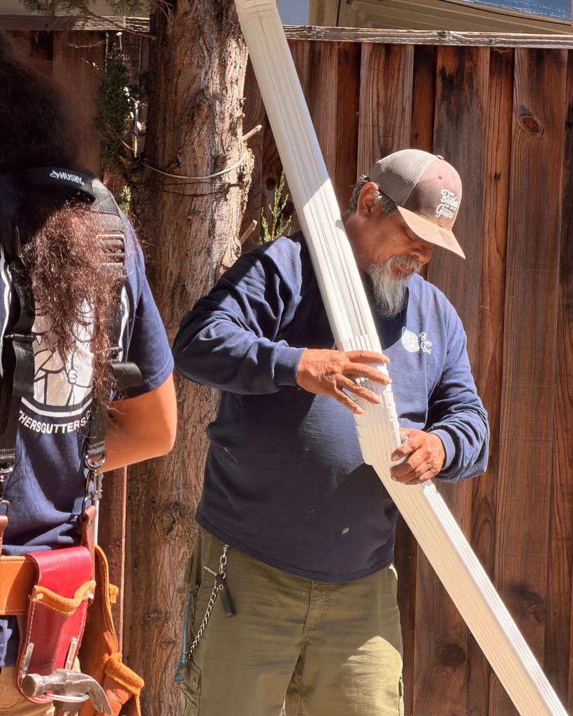 Crew member carrying a downspout to the wall