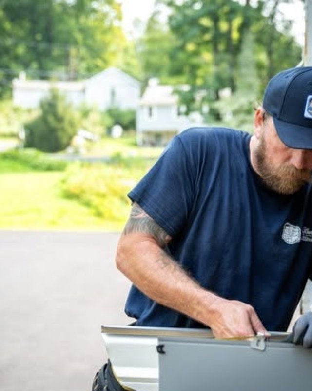 Crew member measuring a seamless gutter run on the truck