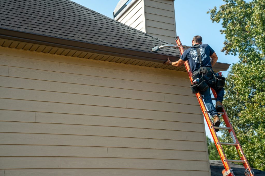 Setting a new gutter along the eave from the ladder