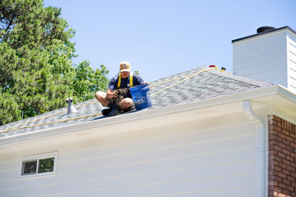 Installer on the roof checking gutters by the chimney